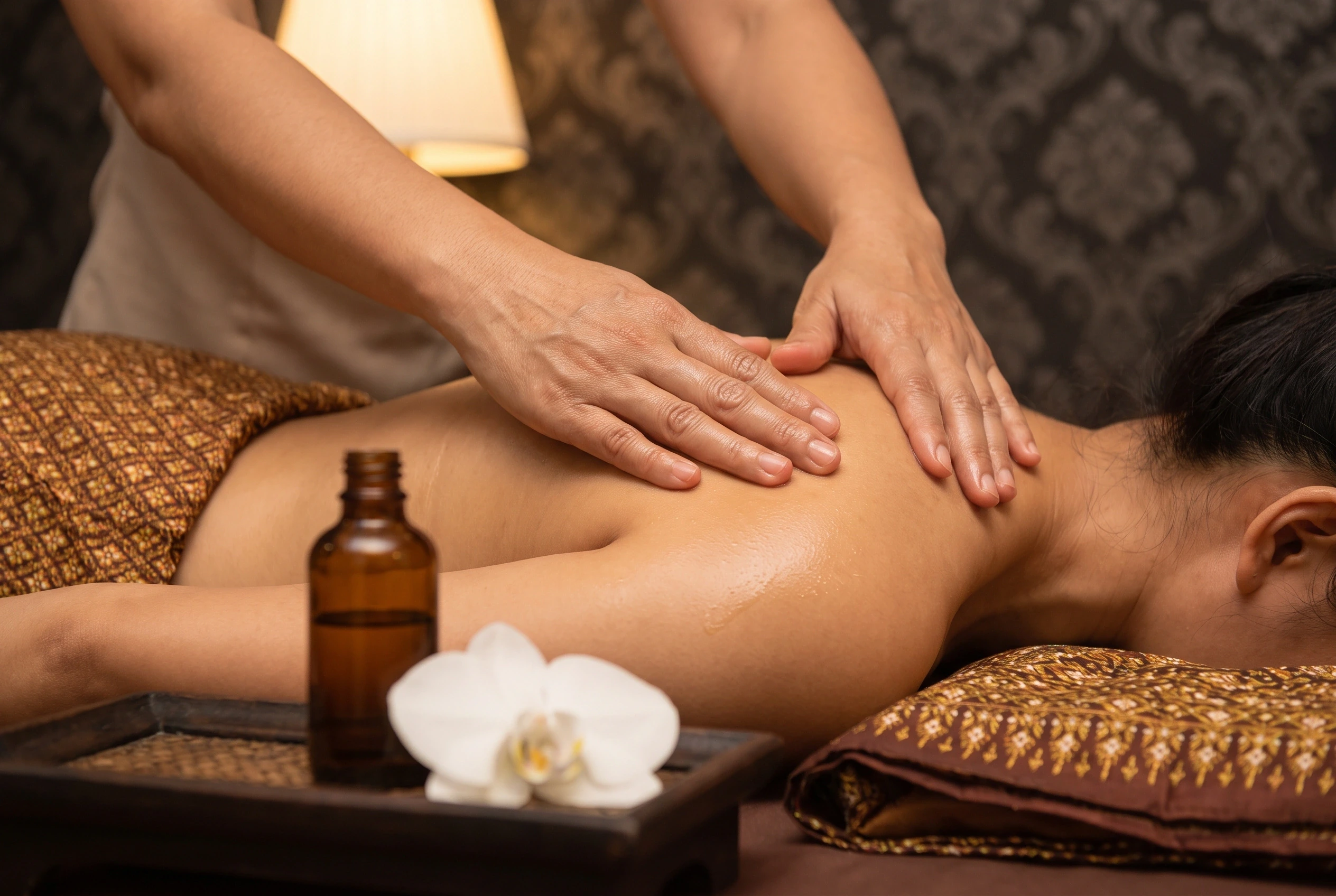 Aromatherapie-oliemassage van de schouder, met etherische olie en een orchidee