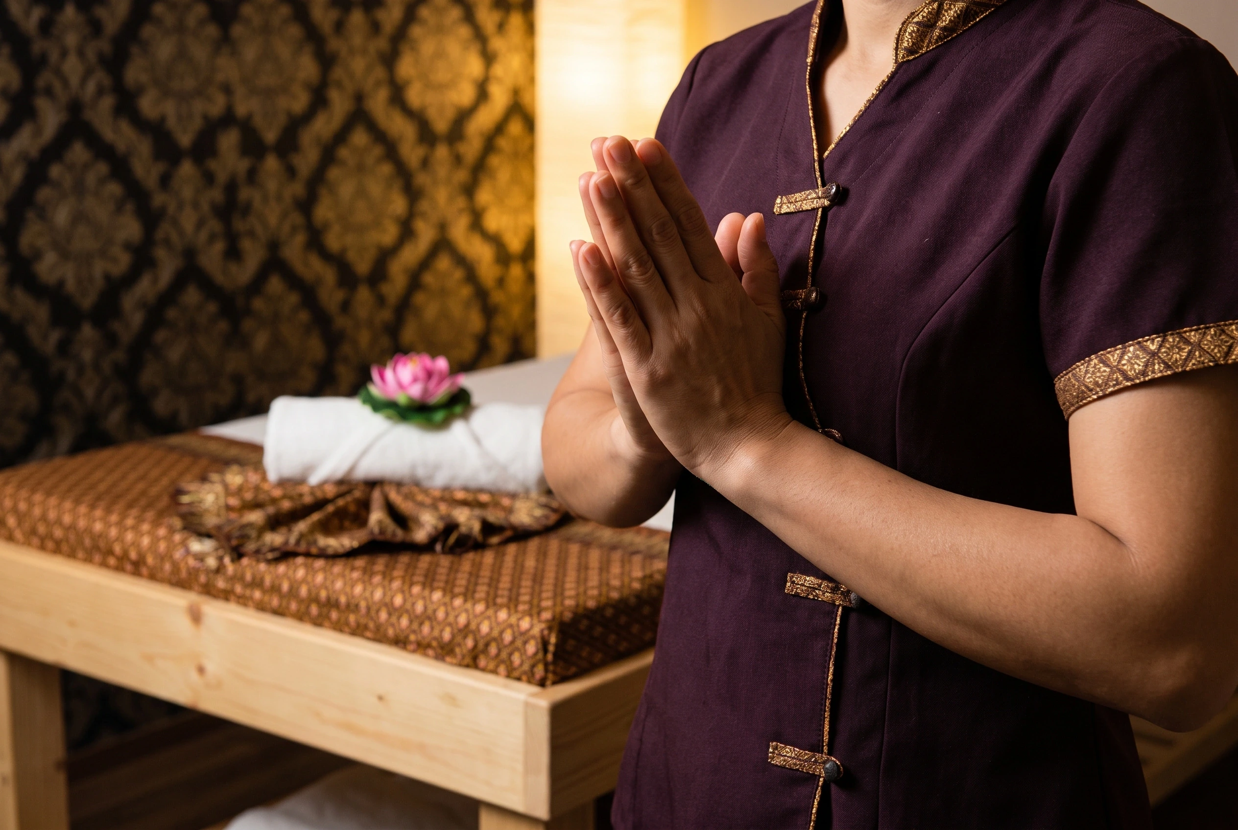Massagetherapeut in Thais uniform groet met gevouwen handen (wai)